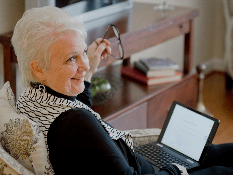 Senior woman sitting in chair and using laptop computer