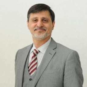Majd Alwan headshot in gray suit with striped tie